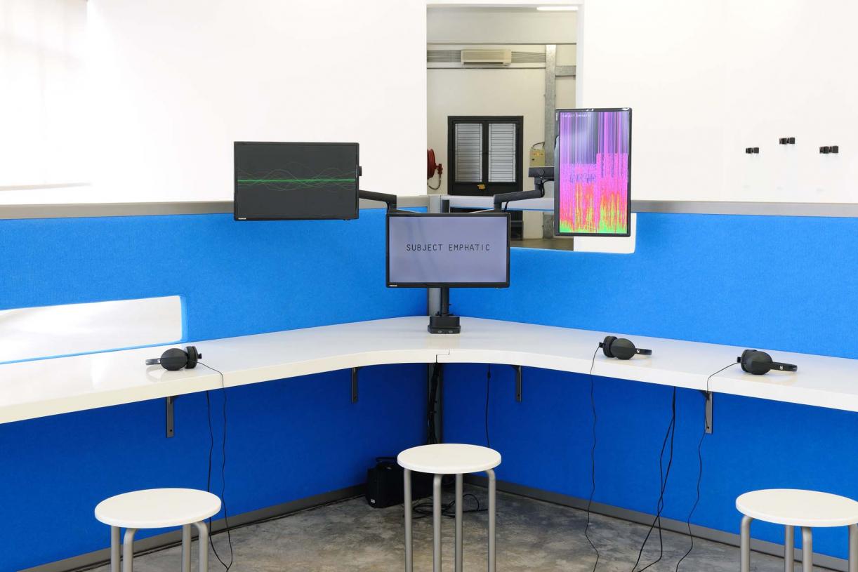 The Whole Truth, 2012, Reverse engineered lie detector, 3 channel video, stereo sound, desk, 3 chairs, 3 artificial plants, 24 minutes, 612 x 435 x 190 cm, Ed.5 + 2 AP