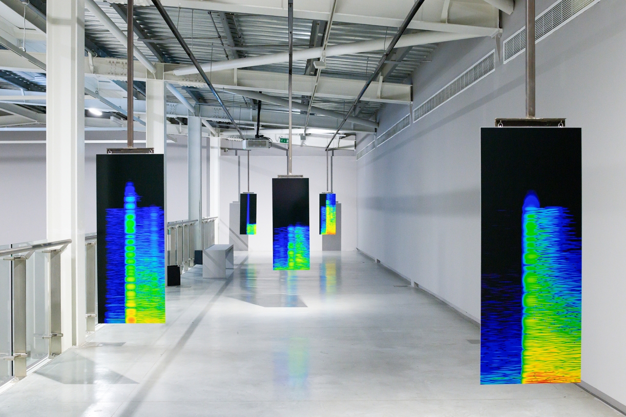 Earshot, 2016. Single-channel video with colour and sound; 21 minutes 47 seconds, monitor, speakers, 6 colour C-print photographs on paper mounted on aluminium with steel display structure; 125 x 50 cm each. Installation view: The Sonic Image, Sharjah Art Foundation, 2022. Commissioned by Portikus, Frankfurt. 