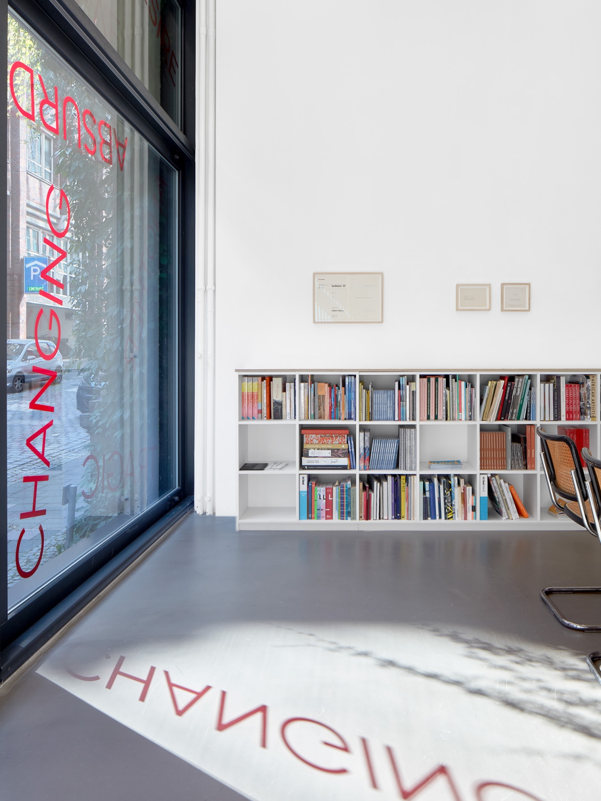 Untitled, 2024, 19 red foil words on window, Dimensions variable