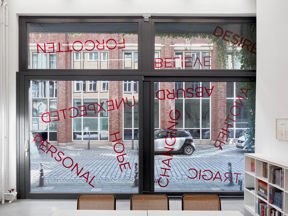 Untitled, 2024, 19 red foil words on window, Dimensions variable
