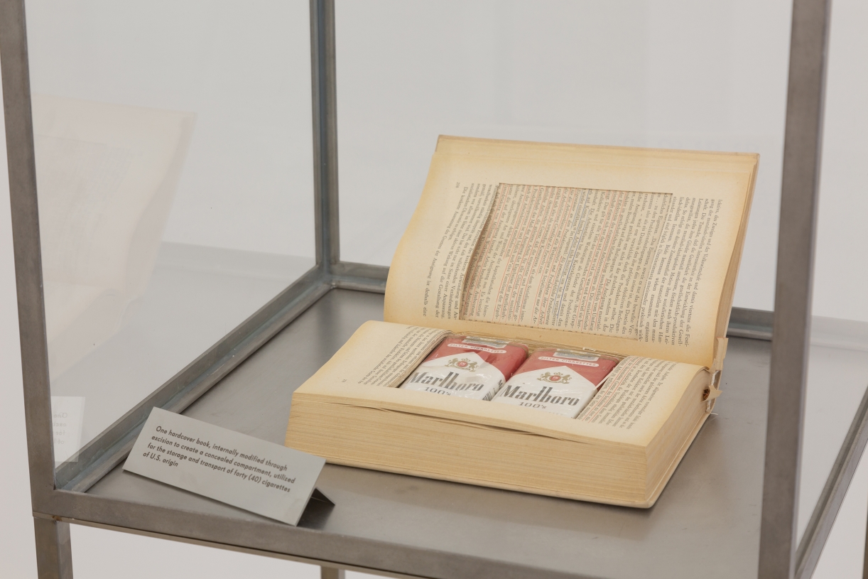 Sung Tieu, Object of Suspicion, 2025, Book, American cigarettes, perspex, stainless steel, glass, 151 × 41 × 41 cm, unique